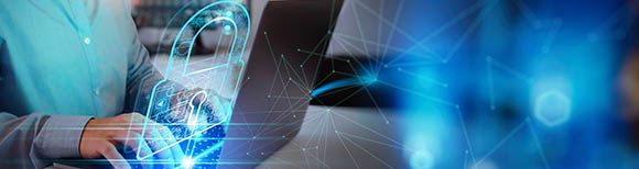 Decorative. A glowing drawing of a padlock and network superimposed over a person seated at a desk with a computer.