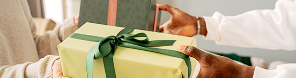 a pair of hands passing two wrapped gifts to another pair of hands