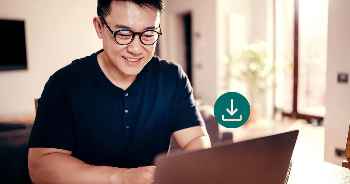 Decorative. A man wearing eyeglasses and a short-sleeved shirt is on the left. He sits at a desk with a laptop computer. A download icon is superimposed above the laptop. To his left is a window.