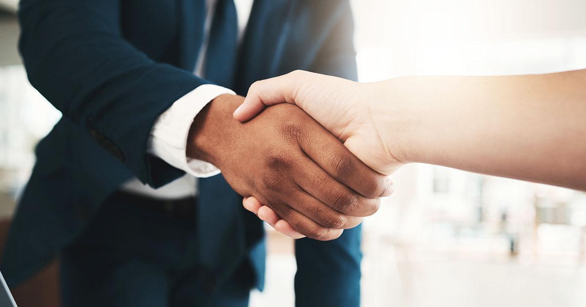 Two people shaking hands over a desk