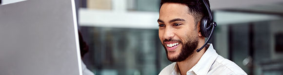 Decorative. A man seated at a desk at work smiles while looking at his desktop monitor.