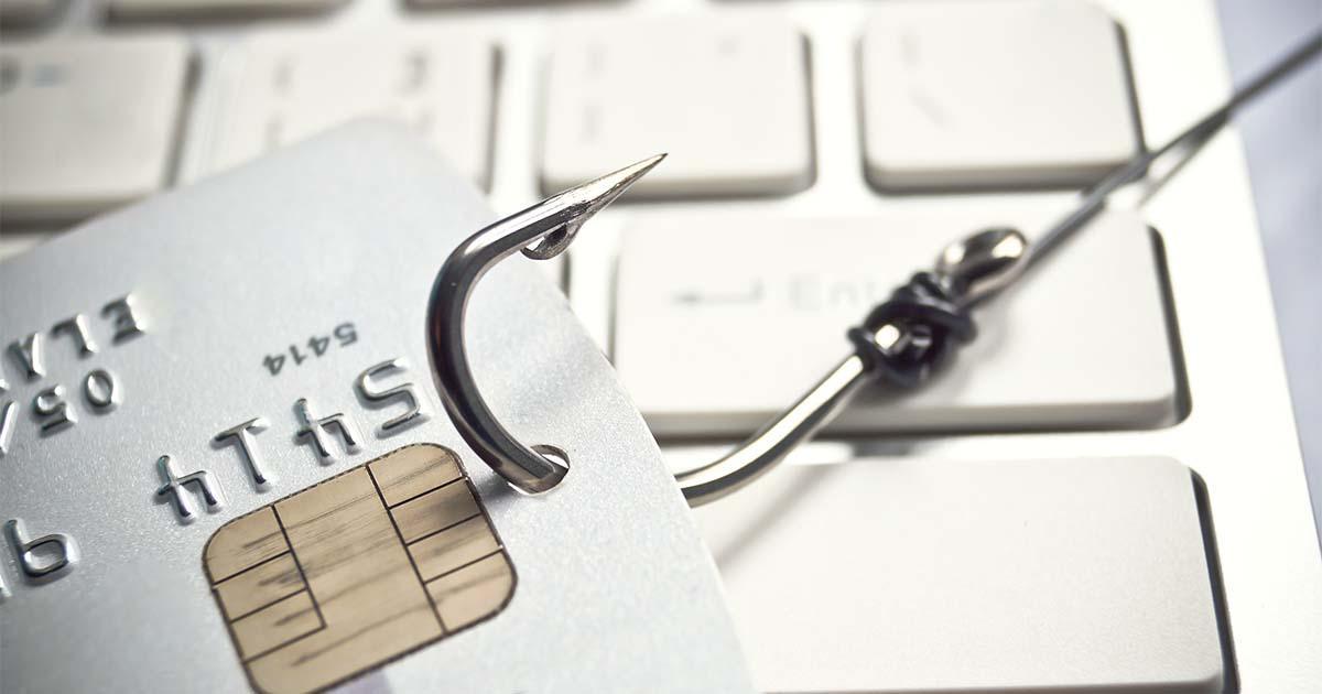 Illustrative. A large metal fishing hook pulls a credit card across a computer keyboard. This illustrates the concept of 