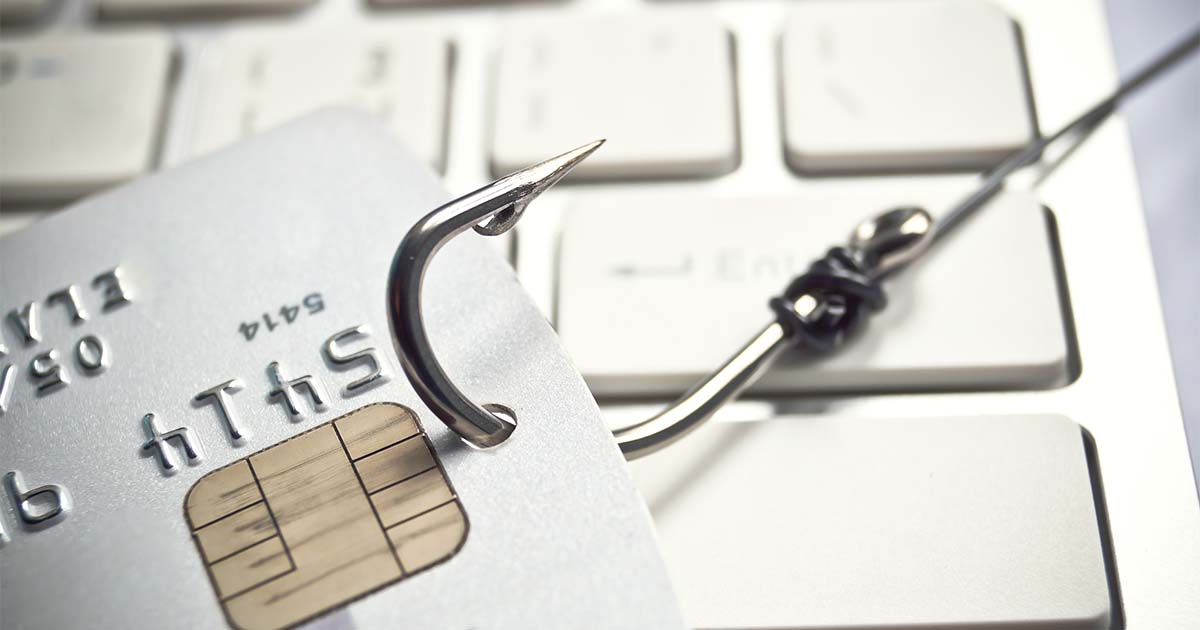 Illustrative. A large metal fishing hook pulls a credit card across a computer keyboard. This illustrates the concept of 