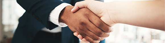 Two people shaking hands over a desk