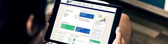 An over-the-shoulder view of a man looking at a computer tablet in his hands. On the screen of the tablet is the myVRS website. Illustrative only.