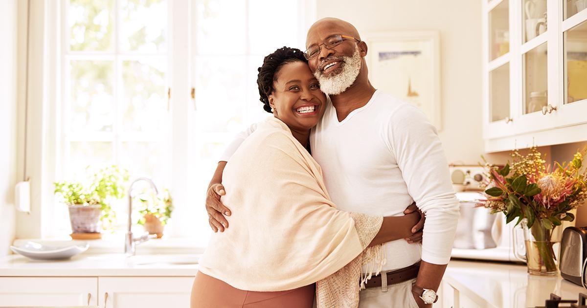 Decorative. A smiling older couple embrace in their large, luxury kitchen.