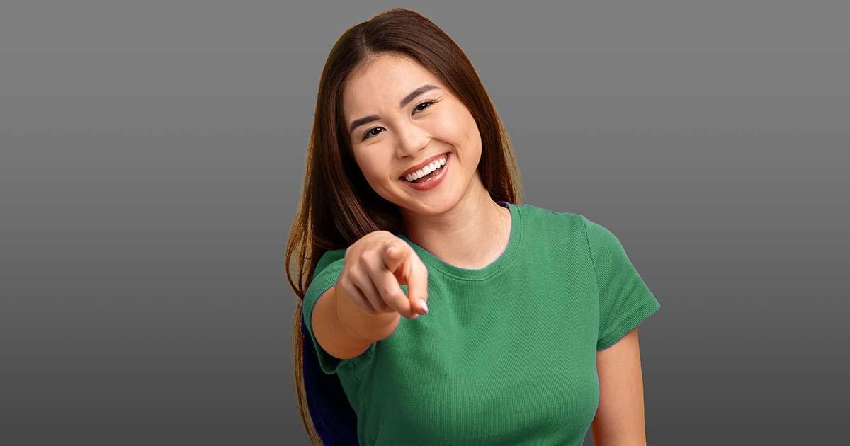 Decorative. Woman wearing a t-shirt smiles and points at the viewer.